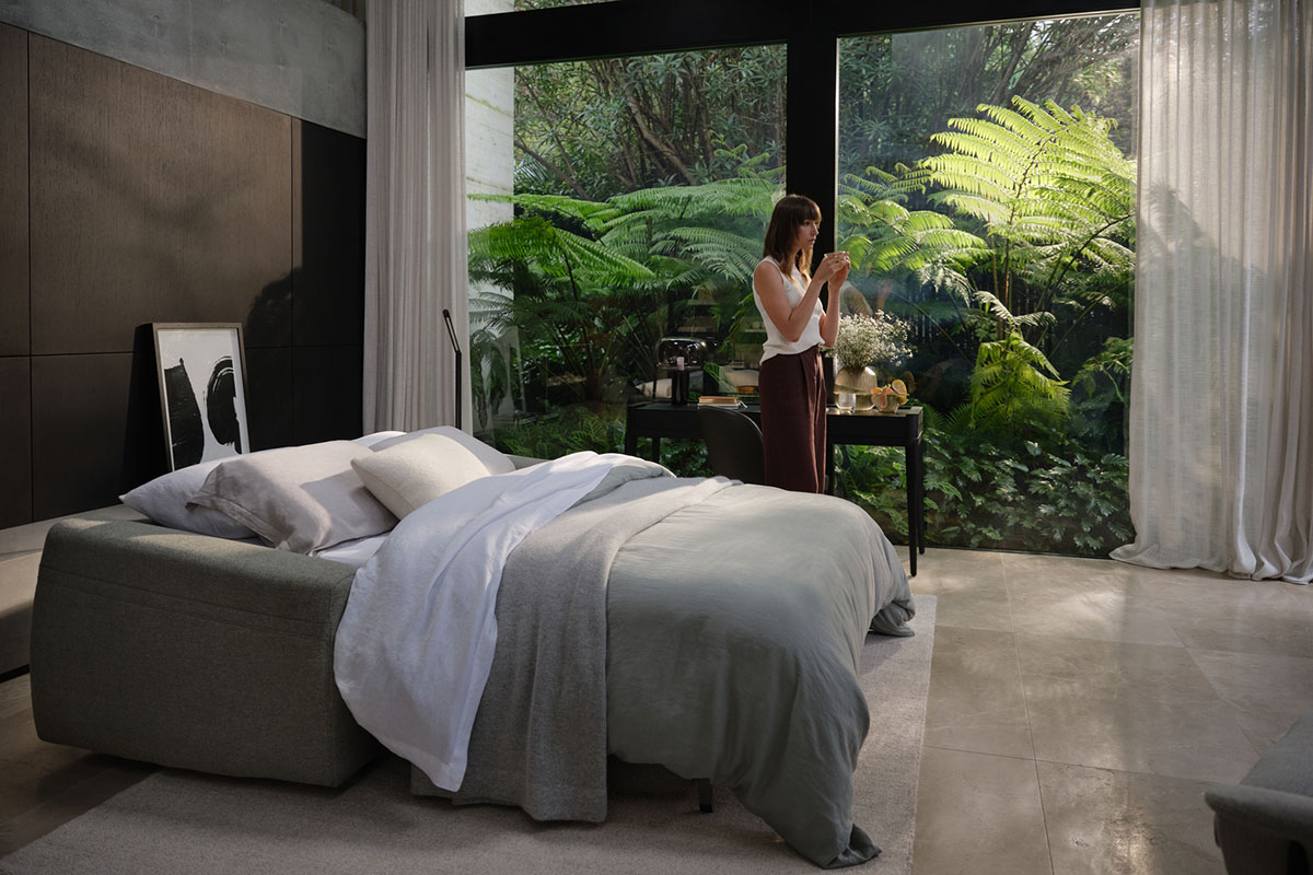 Elegant bedroom with a modern sofa bed and garden views through floor-to-ceiling windows.